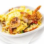 Cajun Shrimp Breakfast Skillet topped with grilled Cajun shrimp, fluffy scrambled eggs, green peppers, onions, tomatoes, Monterey Jack and Cheddar cheese