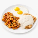 Crispy chicken fried chicken topped with rich white gravy, served with two fried eggs and seasoned diced potatoes at The Eggsquisite Cafe