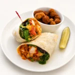 Buffalo Chicken Sandwich or Wrap at Eggsquisite Cafe with hand-breaded buffalo chicken, lettuce, tomatoes, Swiss cheese, and special sauce.