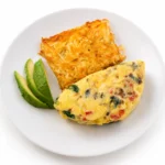 Cowboy Omelette at Eggsquisite Cafe with bacon, ham, sausage, and Monterey Jack and cheddar cheese, served with two breakfast sides.