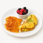 Denver Omelette at Eggsquisite Cafe with ham, green peppers, onions, and Monterey Jack and cheddar cheese, served with two breakfast sides.