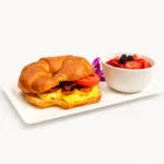 Breakfast Sandwich at Eggsquisite Cafe with bacon, a fried egg, and American cheese on a croissant.