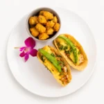 Breakfast Tacos at Eggsquisite Cafe with scrambled eggs, chorizo or chicken carnitas, tater tots, American cheese, pico de gallo, and chipotle hollandaise.