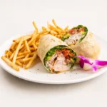 Turkey Avocado Wrap at Eggsquisite Cafe with sliced turkey, bacon, avocado, lettuce, tomatoes, and Monterey Jack and cheddar cheese.