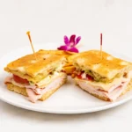 Turkey Pesto Panini at Eggsquisite Cafe with turkey, tomatoes, Swiss cheese, and pesto mayo on grilled focaccia bread.