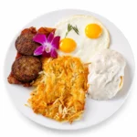 Southern Combo at Eggsquisite Cafe with a biscuit topped with homemade sausage gravy, two eggs, sausage patties, bacon, and hash browns.