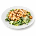 Chicken Caesar Salad at Eggsquisite Cafe with grilled chicken breast, romaine lettuce, Parmesan cheese, croutons, and creamy Caesar dressing.