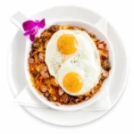 Meat Lovers Skillet at Eggsquisite Cafe with hash browns, two eggs, bacon, ham, sausage, and Monterey Jack and cheddar cheese.